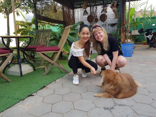 dos jovencitas arrodilladas junto a un perro marrón en Bloom Garden Bed & Breakfast en Siem Riep
