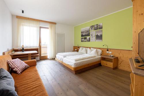 a bedroom with a bed and a table and a couch at Grünwald in Salorno
