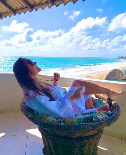 a woman sitting in a wicker chair on the beach at Pousada Maracabana Spa in Porto De Galinhas