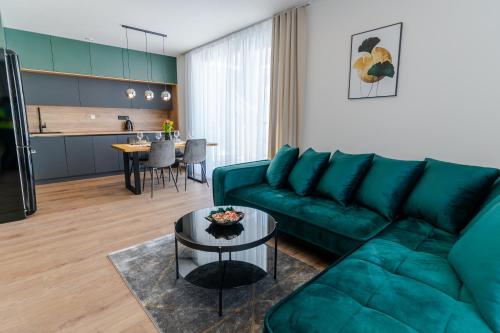 Avocado apartment Victory port في ليبتوفسكي ميكولاش: غرفة معيشة مع أريكة خضراء وطاولة