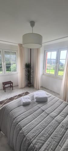 Cama grande en habitación blanca con ventanas en Hostal Restaurante Os Faroles playa de Esteiro en Lago