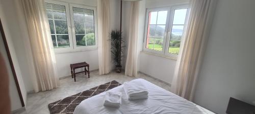 ein weißes Schlafzimmer mit einem Bett und zwei Fenstern in der Unterkunft Hostal Restaurante Os Faroles playa de Esteiro in Lago