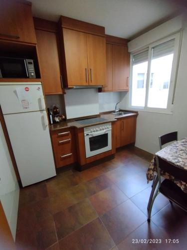 a kitchen with wooden cabinets and a white refrigerator at Piso JS in Ourense