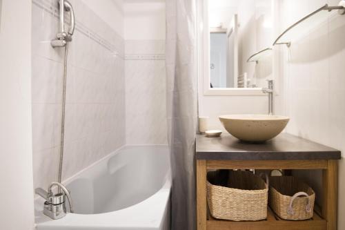 een badkamer met een wit bad en een wastafel bij Studio "Orneau" proche du port de ST MARTIN in Saint-Martin-de-Ré