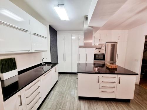 a kitchen with white cabinets and black counter tops at El Piso de María in Vigo
