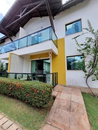 a large white and yellow house with a balcony at Casa em Condomínio Fechado com Sauna e Piscina in Salinópolis