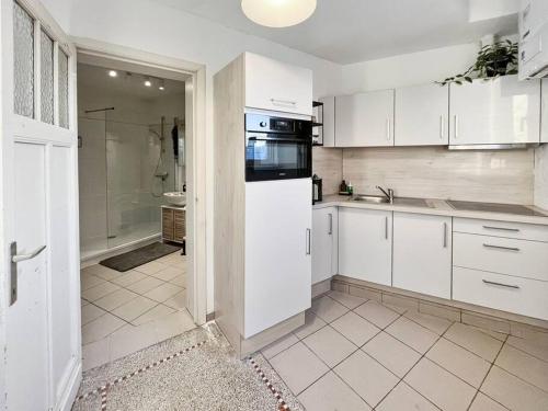 een keuken met witte kasten, een wastafel en een koelkast bij Cozy Antwerp - Zurenborg Skyline FREE PARKING in Antwerpen