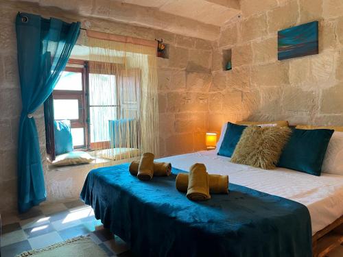 a bedroom with a large bed with blue sheets at Haven Farmhouse B&B in Għarb