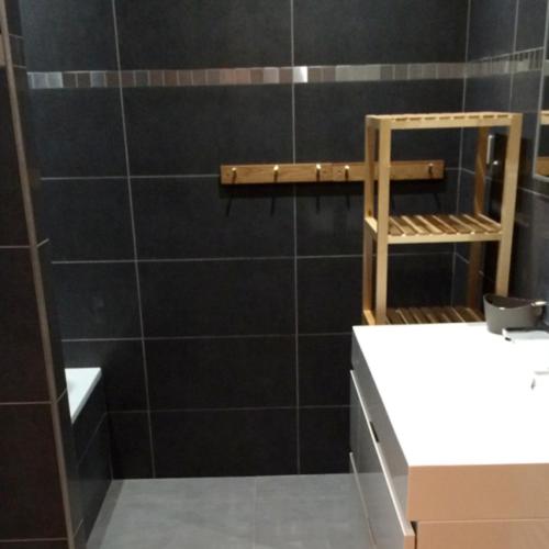 a bathroom with a black tiled wall and a shelf at Les Etoiles de Vonnes 2 in Châtel
