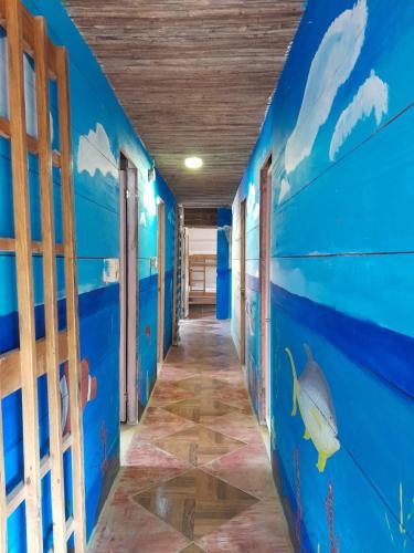 a hallway in a house with blue walls and a fish mural at HOSTAL BELLEZA TROPICAL in Moñitos