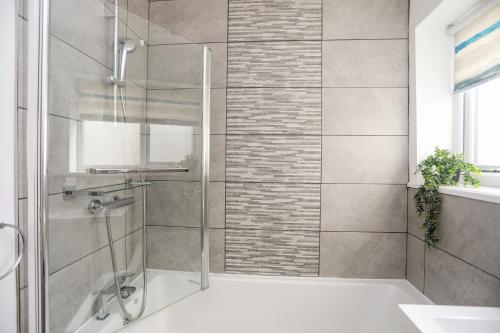 a bathroom with a shower with a glass door at Tinkers Patch in Benllech