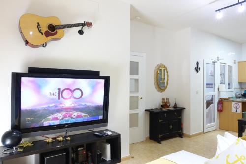 Una sala de estar con un televisor y una guitarra en la pared. en Best Valencia Beach Rooms-Shared Flat, en Valencia