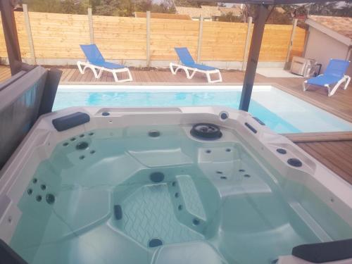 una vasca idromassaggio con due sedie e una piscina di Magnifique Villa sur le Bassin d'Arcachon - JACUZZI+PISCINE - 8à10pers a Biganos