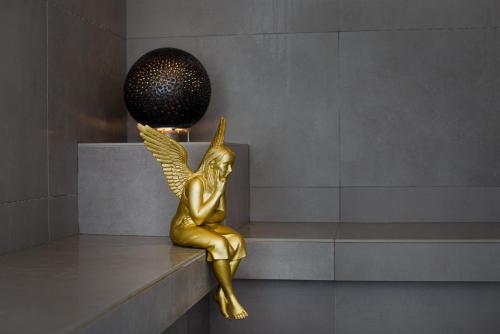 a gold statue of an angel sitting on a ledge at hirschen dornbirn - das boutiquestyle hotel - skyrelax & wellness im rooftop in Dornbirn