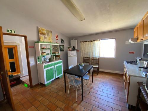 eine Küche mit einem Tisch, einem Kühlschrank und einem Tisch in der Unterkunft Faroway Hostel in Faro