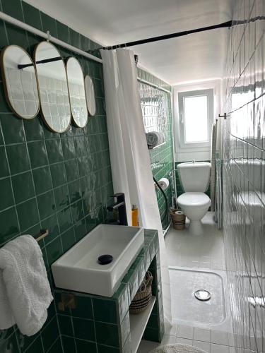 La salle de bains carrelée de couleur verte est pourvue d'un lavabo et de toilettes. dans l'établissement Mansarde à 1 min de la mer, à Nice