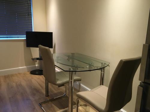 - une table en verre avec des chaises et une télévision dans la chambre dans l'établissement Private One Bedroom Apartment, à Slades Green