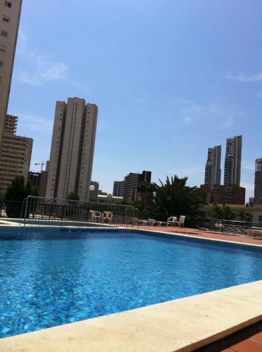 a large swimming pool with a city in the background at Luxmar Apartaments in Benidorm
