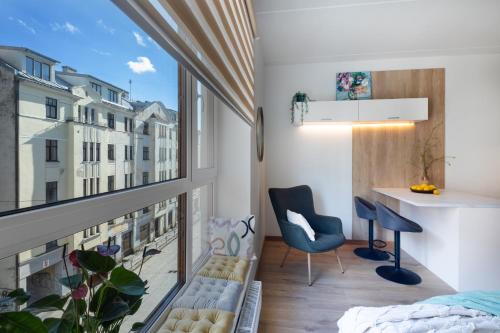 een klein appartement met een balkon met een bureau en een stoel bij Leonardo Studio Apartments In City Center in Rīga
