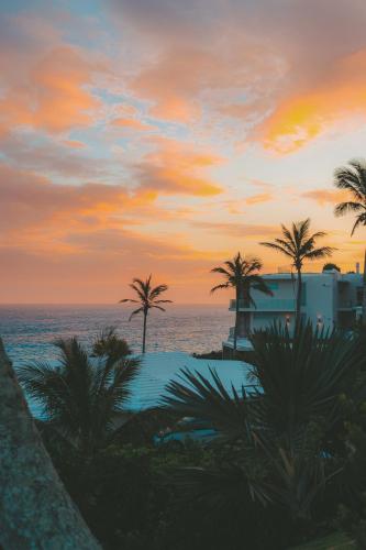 a sunset over the ocean with palm trees and a resort at Azura Bermuda in Bermuda