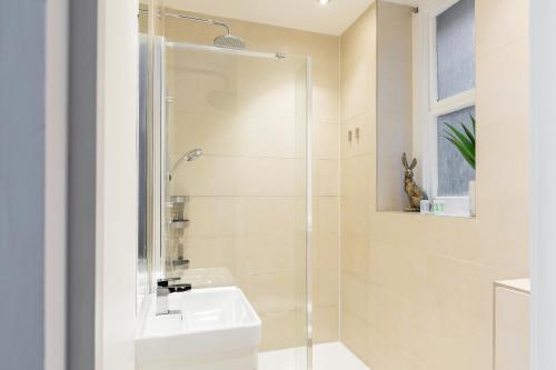 a white bathroom with a shower and a sink at The Victoria Flats in London