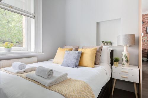 a bedroom with a white bed with towels on it at The Victoria Flats in London