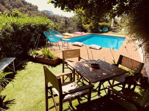 - une table et des chaises à côté de la piscine dans l'établissement Le Saint Paul appartements dans villa provençale, à Saint-Paul-de-Vence