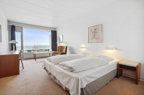 a bedroom with two beds and a desk and a window at Hotel Østersø in Aabenraa