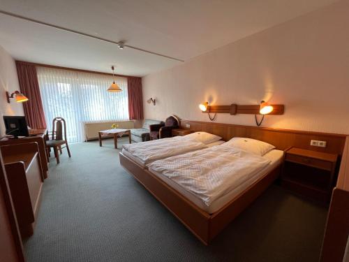 a bedroom with a large bed and a living room at Hotel am Stern Uelzen in Uelzen