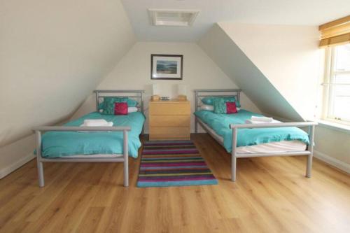 un dormitorio en el ático con 2 camas y una escalera en Castle View Stornoway, en Stornoway