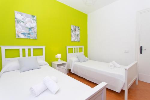 two beds in a room with green walls at Villa Asarel by Sonne Villas in Cala Galdana