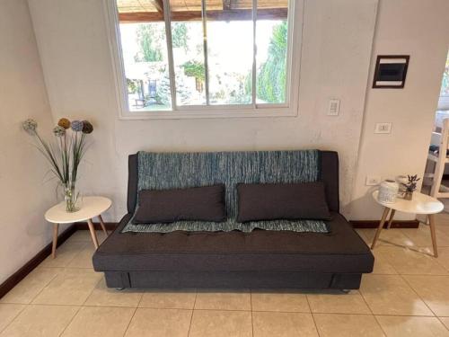 a couch in a room with two tables and a window at Cabaña Chacras de Caro in Chacras de Coria