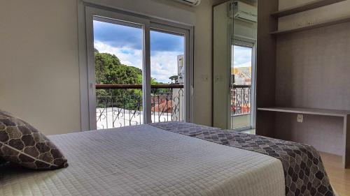 een slaapkamer met een bed en een groot raam bij Residencial Dona Virgínia Centro in Canela