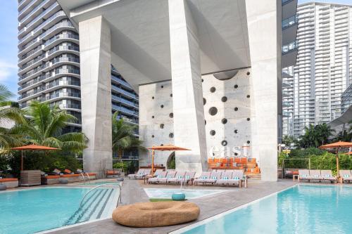 un hotel con piscina con sillas y un gran edificio en EAST Miami Residences en Miami