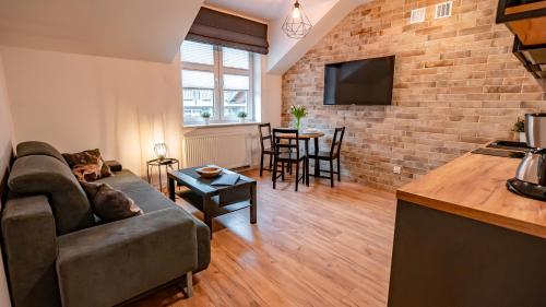 a living room with a couch and a brick wall at Apartamenty Sun & Snow Centrum Cicha in Krynica Zdrój