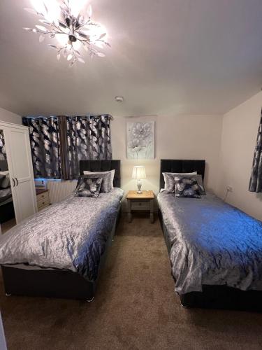 a bedroom with two beds and a chandelier at Edge of Glastonbury and Street - Large Ground Floor 3 BD With Parking, 4 Single and 1 Double Bed in Street