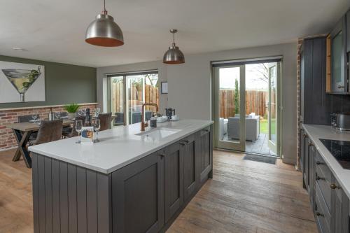 a large kitchen with a large island in the middle at Designer Cotswold post house with external sauna in Tetbury