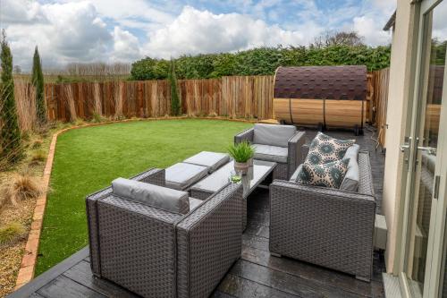 a patio with two wicker chairs and a table at Designer Cotswold post house with external sauna in Tetbury