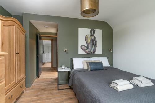 a bedroom with a large bed with green walls at Designer Cotswold post house with external sauna in Tetbury