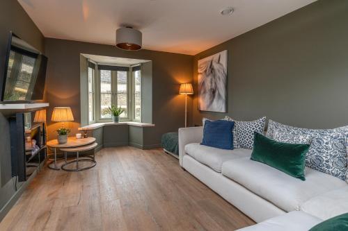 a living room with a white couch and blue pillows at Designer Cotswold post house with external sauna in Tetbury