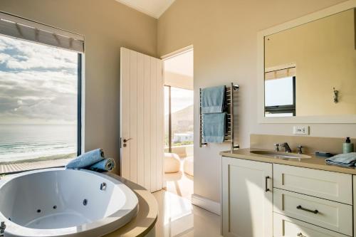 a bathroom with a large white tub and a window at Ocean's Horizon Beach House in Scarborough