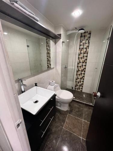 een badkamer met een wastafel, een toilet en een spiegel bij Hermoso apartaestudio con parqueadero in Bogota