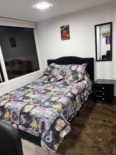 een slaapkamer met een bed met een dekbed en een raam bij Hermoso apartaestudio con parqueadero in Bogota