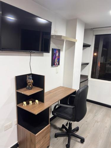 een kantoor met een bureau, een stoel en een televisie bij Hermoso apartaestudio con parqueadero in Bogota