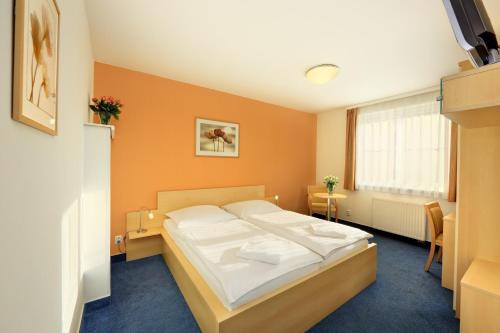 a bedroom with a bed in a room with orange walls at Penzion Krumlov - Massage studio in Český Krumlov
