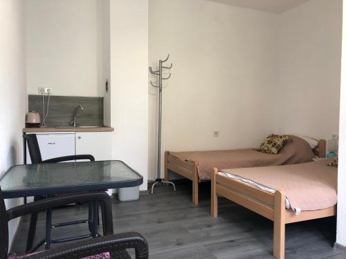 Zimmer mit 2 Betten, einem Tisch und einem Waschbecken in der Unterkunft Miki in Sarajevo