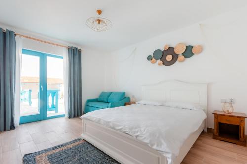 1 dormitorio con 1 cama blanca y 1 silla azul en Vila Mavis-cazare cu piscina incalzita 1 mai-30 sept, en Mahmudia