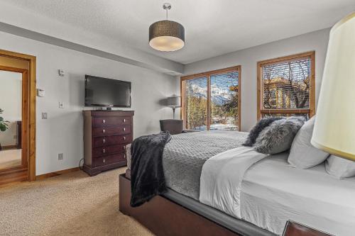 a bedroom with a bed and a flat screen tv at Spring Creek Condo by Canadian Rockies Vacation Rentals in Canmore