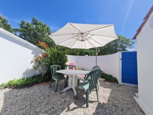 une table avec deux chaises et un parasol dans l'établissement LES MARAICHINES PISCINE COLLECTIVE, à Saint-Jean-de-Monts