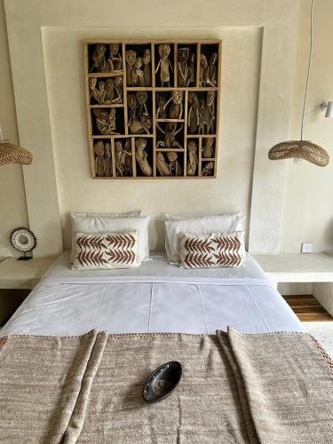 a bedroom with a large white bed with a picture on the wall at Villa Anjing in Nusa Dua